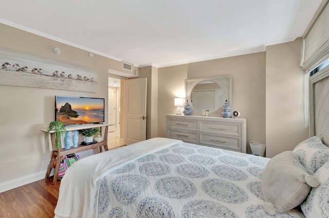 bedroom featuring ornamental molding, visible vents, baseboards, and wood finished floors