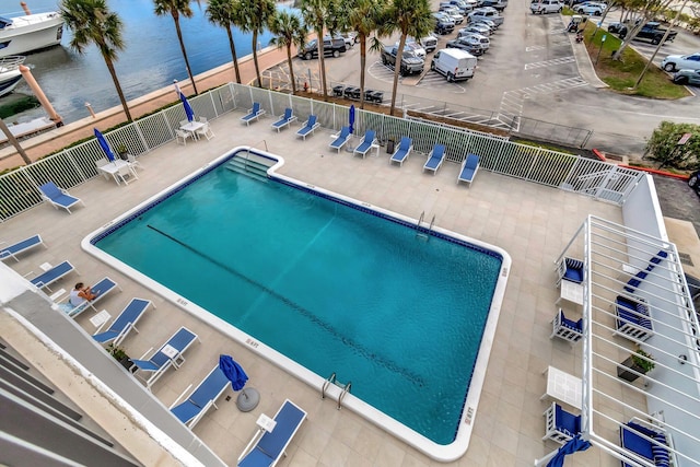 pool with a water view, a patio area, and fence