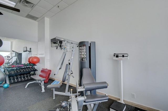 exercise room with visible vents, a paneled ceiling, and baseboards