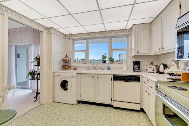 kitchen featuring washer / dryer, sink, a paneled ceiling, and white dishwasher