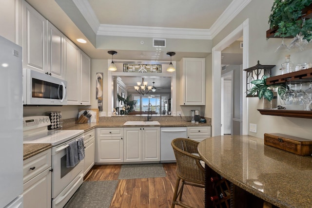 kitchen with sink, white appliances, white cabinetry, hanging light fixtures, and dark stone counters