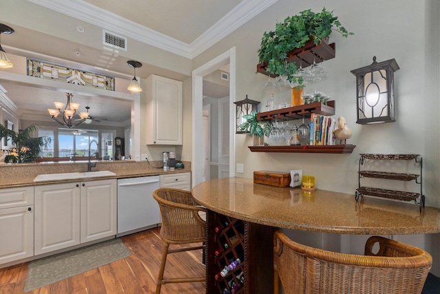 kitchen featuring sink, a breakfast bar area, dishwasher, hanging light fixtures, and white cabinets