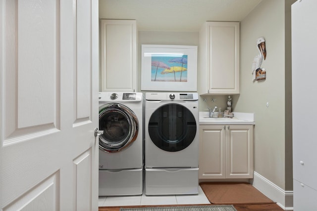 clothes washing area with washer and dryer, sink, and cabinets