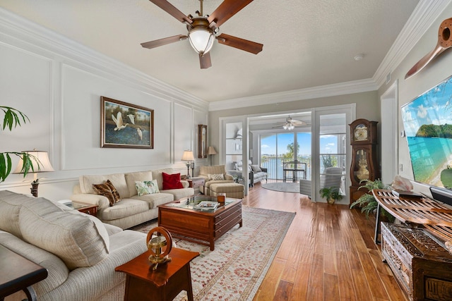 living room with crown molding, ceiling fan, light hardwood / wood-style floors, and a textured ceiling