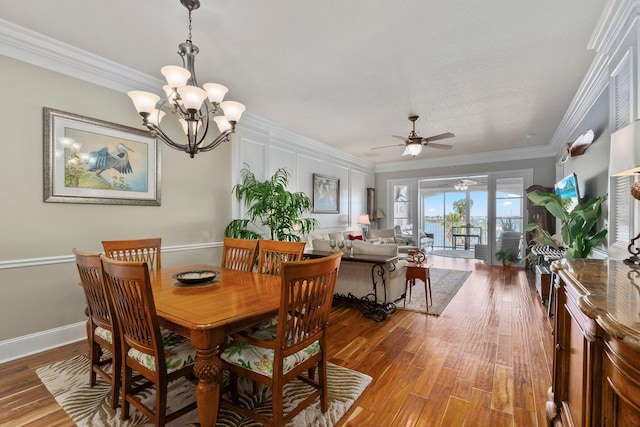 dining room featuring crown molding, wood-type flooring, and ceiling fan with notable chandelier