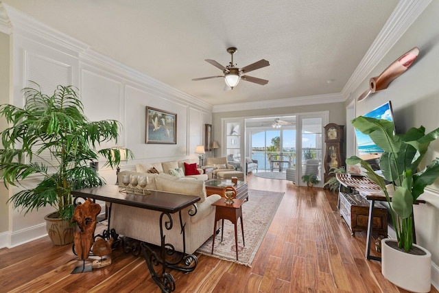 living room featuring crown molding, ceiling fan, hardwood / wood-style floors, and a textured ceiling