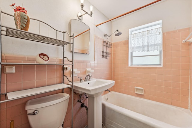 full bathroom with tiled shower / bath, toilet, sink, and tile walls