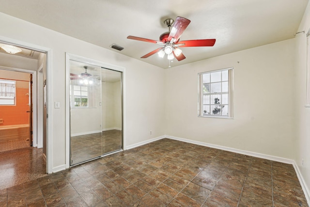 unfurnished bedroom featuring multiple windows, ceiling fan, and a closet