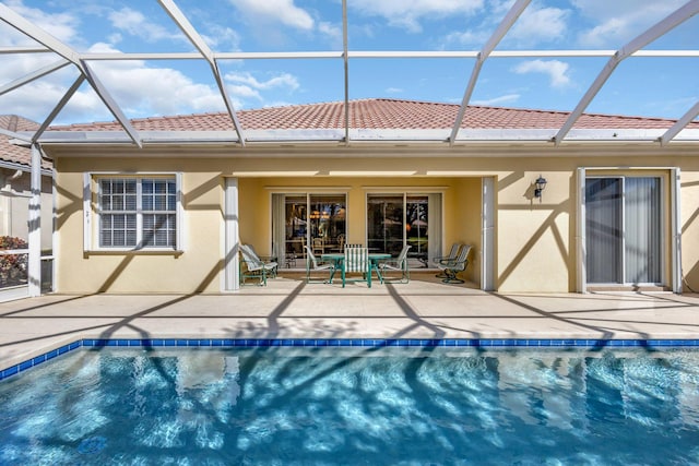 rear view of house featuring a patio and glass enclosure