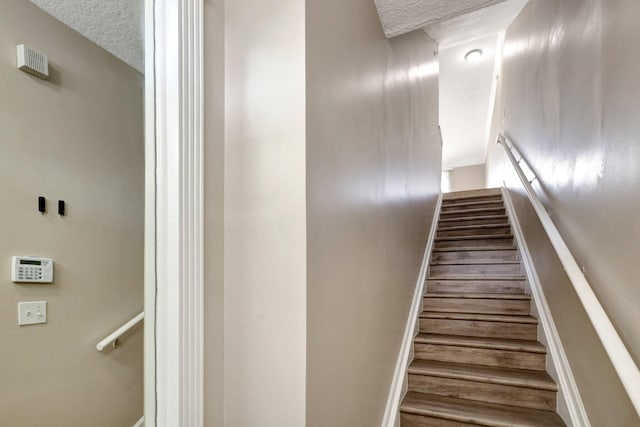 staircase featuring a textured ceiling