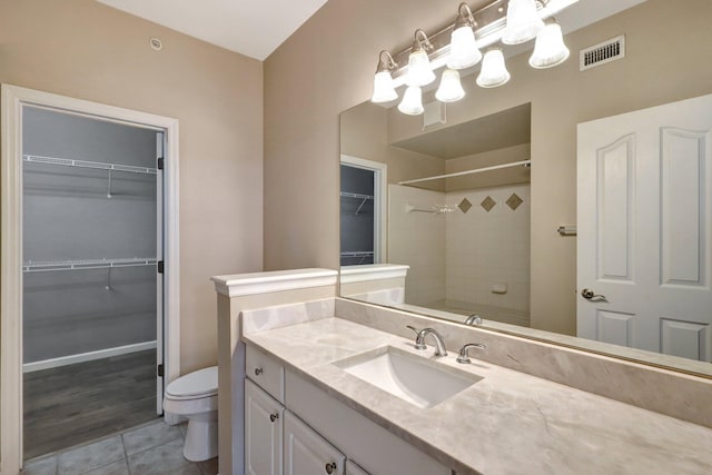 bathroom featuring tile patterned flooring, vanity, toilet, and walk in shower