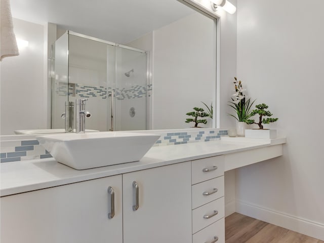 bathroom featuring hardwood / wood-style flooring, vanity, an enclosed shower, and backsplash