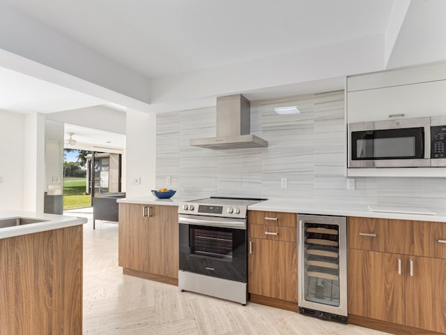 kitchen with sink, appliances with stainless steel finishes, wall chimney range hood, beverage cooler, and backsplash