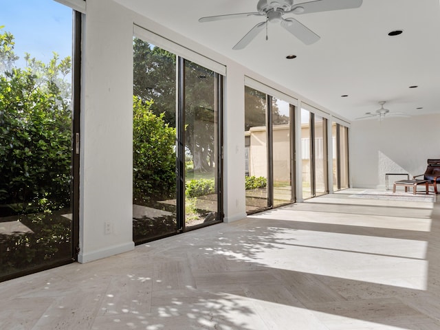 unfurnished sunroom featuring ceiling fan and a wealth of natural light