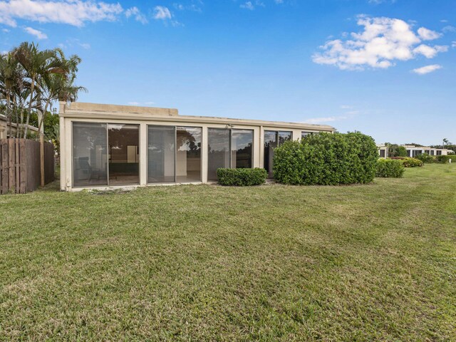 rear view of house with a sunroom and a lawn