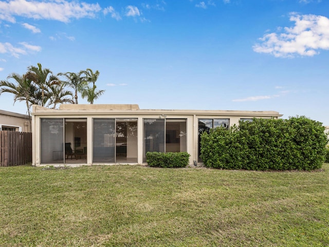 rear view of property featuring a lawn and a sunroom