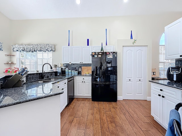 kitchen with white cabinetry, black appliances, dark stone counters, and light wood-type flooring