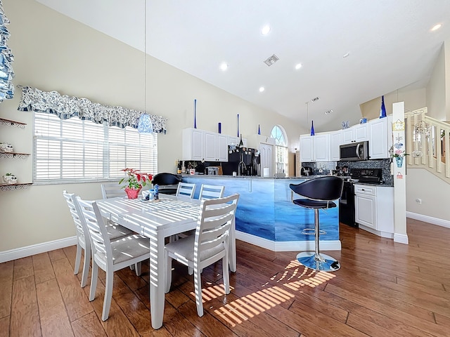 dining space featuring dark hardwood / wood-style floors and high vaulted ceiling