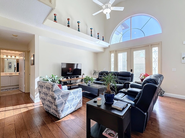 living room featuring wood-type flooring, a towering ceiling, ceiling fan, and french doors