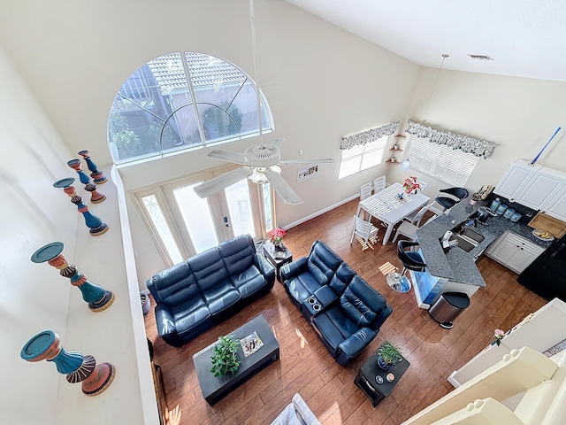 living room with wood-type flooring, high vaulted ceiling, and ceiling fan