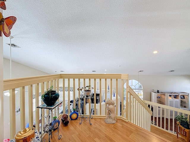 hall with wood-type flooring and a textured ceiling