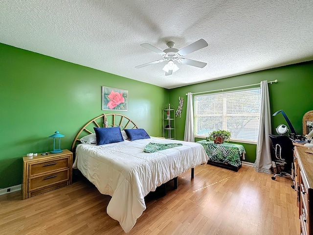 bedroom with a textured ceiling, ceiling fan, and light wood-type flooring