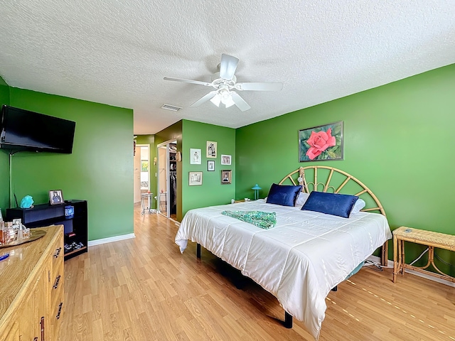 bedroom featuring ceiling fan, a textured ceiling, and light wood-type flooring