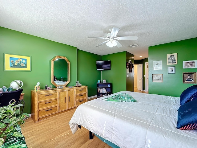 bedroom featuring ceiling fan, wood-type flooring, and a textured ceiling