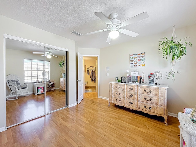 bedroom with ceiling fan, wood-type flooring, a closet, and a textured ceiling