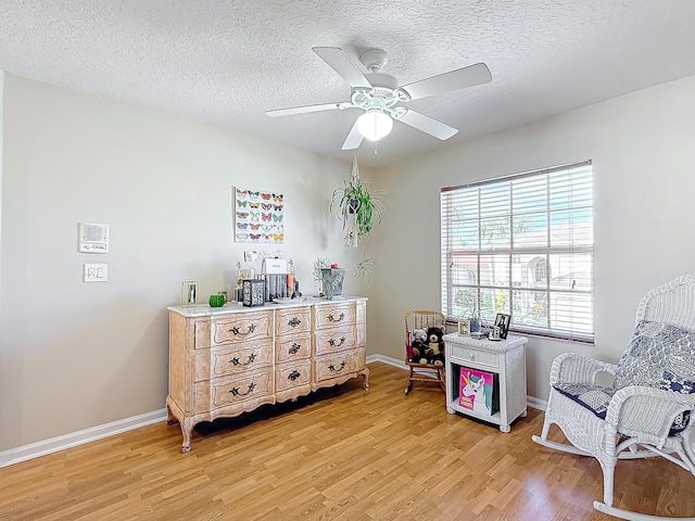 sitting room featuring ceiling fan, light hardwood / wood-style flooring, and a textured ceiling