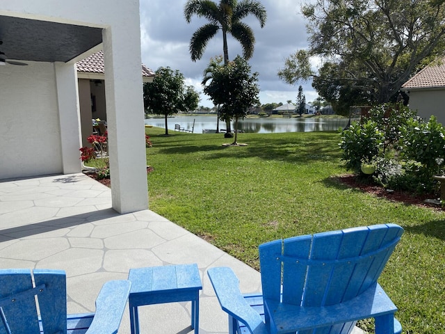 view of yard with a water view, ceiling fan, and a patio area