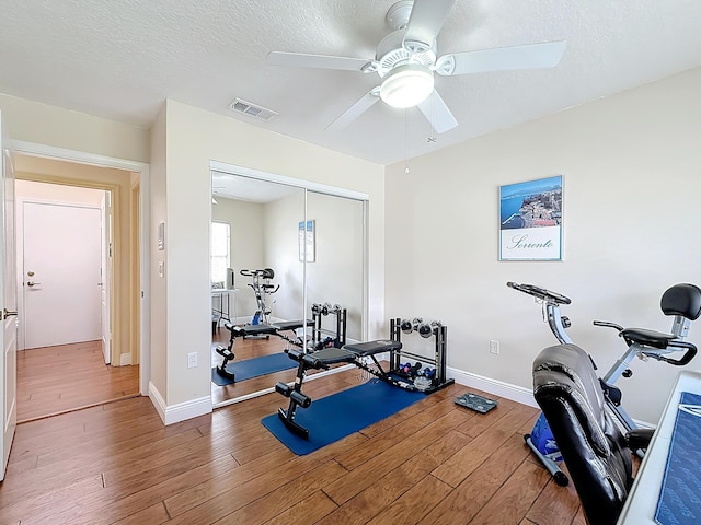 workout room featuring wood-type flooring, ceiling fan, and a textured ceiling