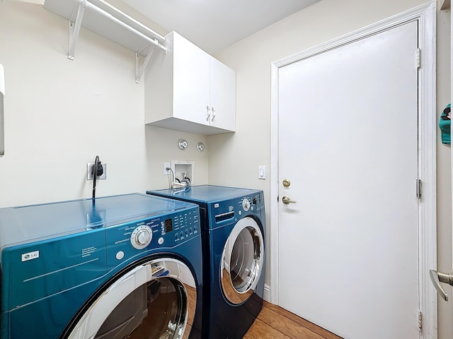 washroom with cabinets, light hardwood / wood-style flooring, and washer and dryer