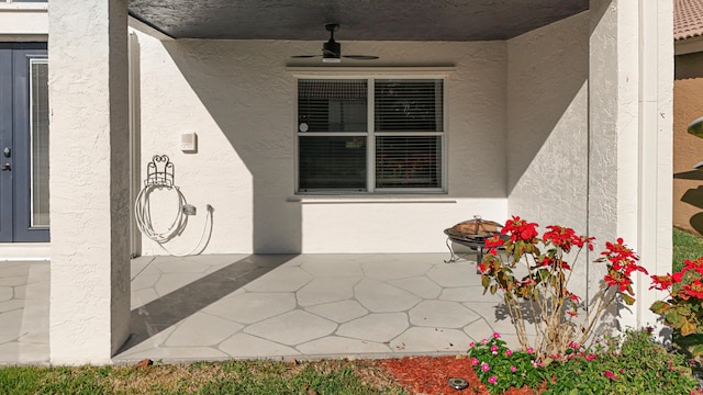 view of exterior entry with ceiling fan and a patio