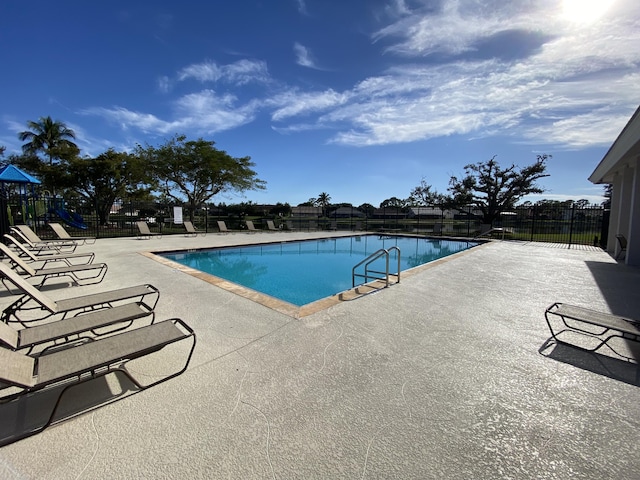 view of pool with a playground and a patio