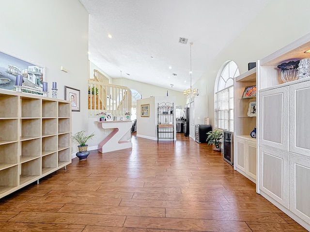 living room featuring wine cooler, a notable chandelier, wood-type flooring, and high vaulted ceiling