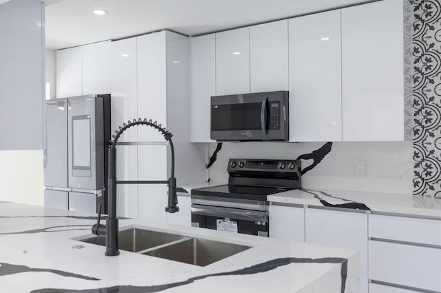 kitchen featuring light stone counters, appliances with stainless steel finishes, and white cabinets