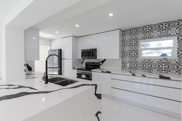 kitchen with stainless steel appliances, white cabinetry, sink, and light stone counters