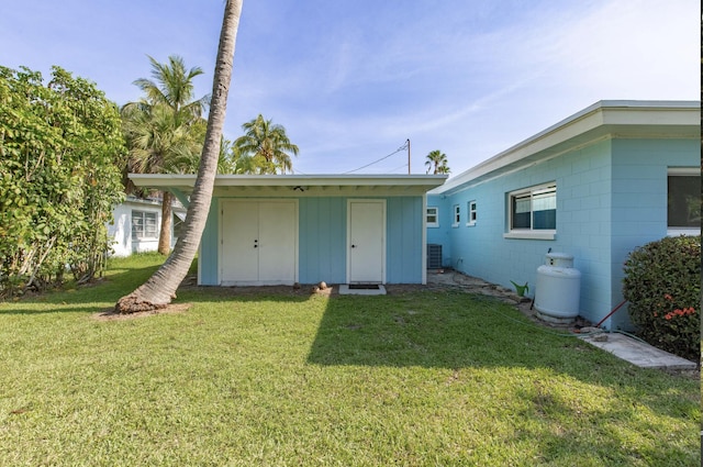 back of property featuring a yard and central AC
