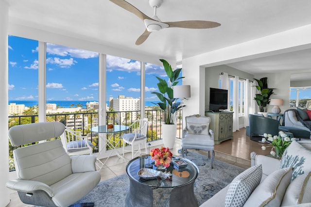 sunroom / solarium featuring a water view and ceiling fan