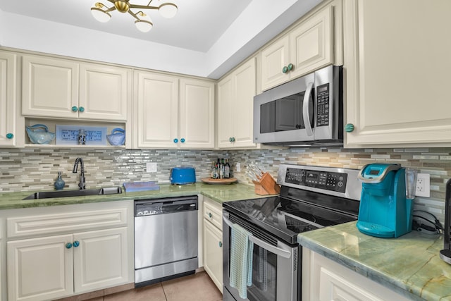 kitchen with sink, backsplash, light tile patterned floors, light stone counters, and stainless steel appliances