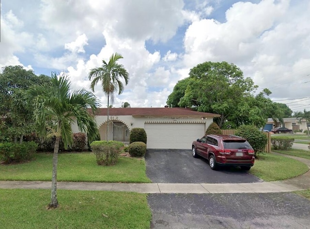 view of front facade with driveway, stucco siding, a garage, and a front yard