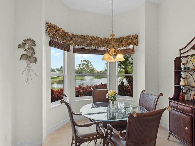 tiled dining space featuring a water view and a notable chandelier