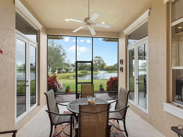 sunroom / solarium featuring a water view, ceiling fan, and french doors