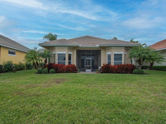 back of property featuring a sunroom and a lawn