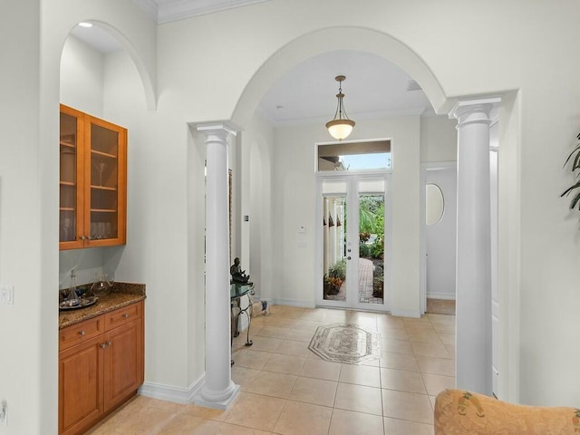 entrance foyer with light tile patterned floors, crown molding, and decorative columns