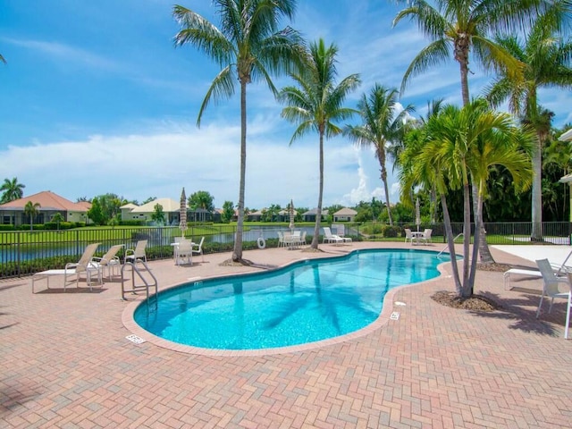 view of pool featuring a water view and a patio