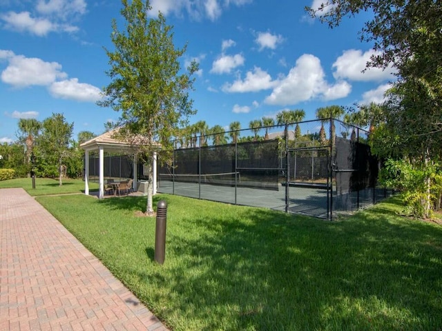 view of tennis court featuring a gazebo and a lawn