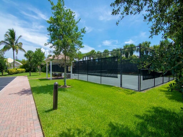 view of tennis court featuring a yard and a gazebo