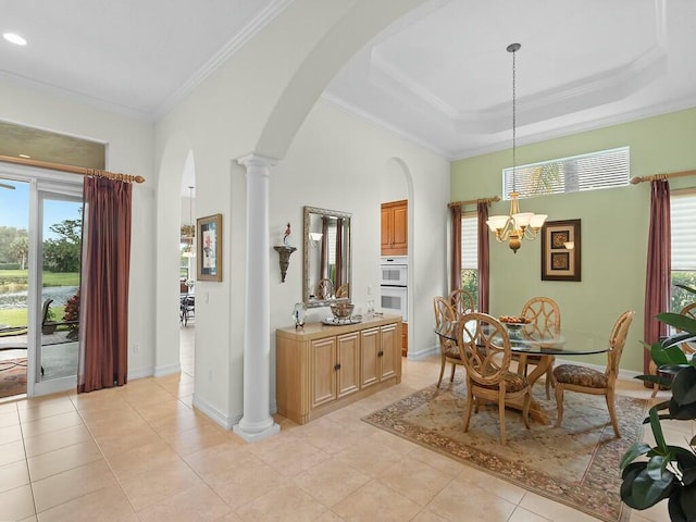 tiled dining room with ornate columns, crown molding, a chandelier, a raised ceiling, and a towering ceiling